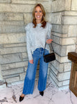 Heather gray round neck long sleeve sweater with gray fringe along the front from shoulders down to hem