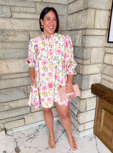 Floral dress with ruffle collar. Button front with pintuck details. Bright pink floral print on short dress with 3/4 sleeves.