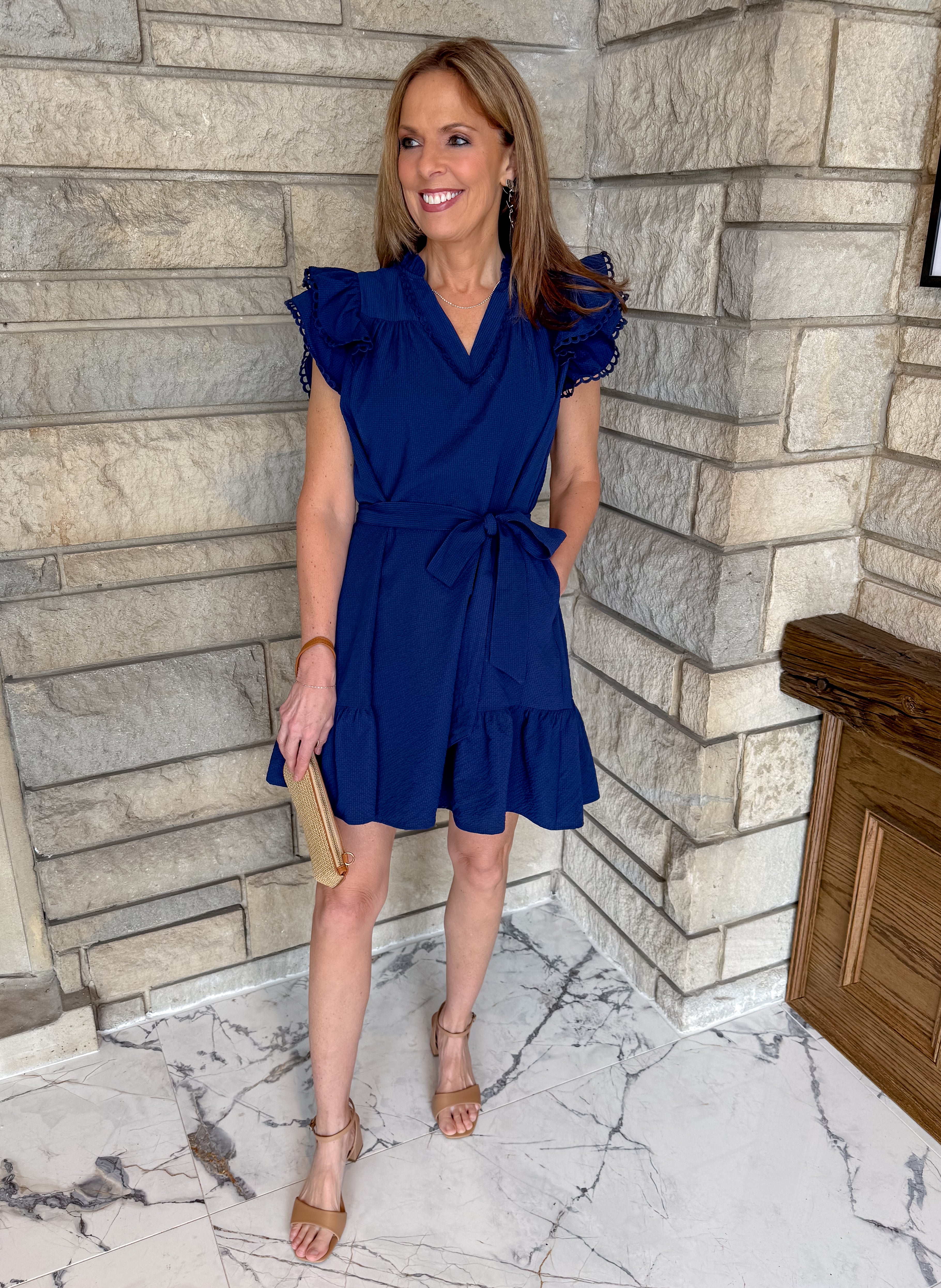 Navy blue dress with ruffle shoulders and flounce hem. Self tie waist belt and v neckline with scallop trim.
