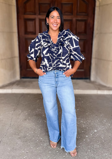 Printed
V-Neckline
Smocked Ruffle Trim and Cuff
3/4 Puff Sleeve
Dark Navy